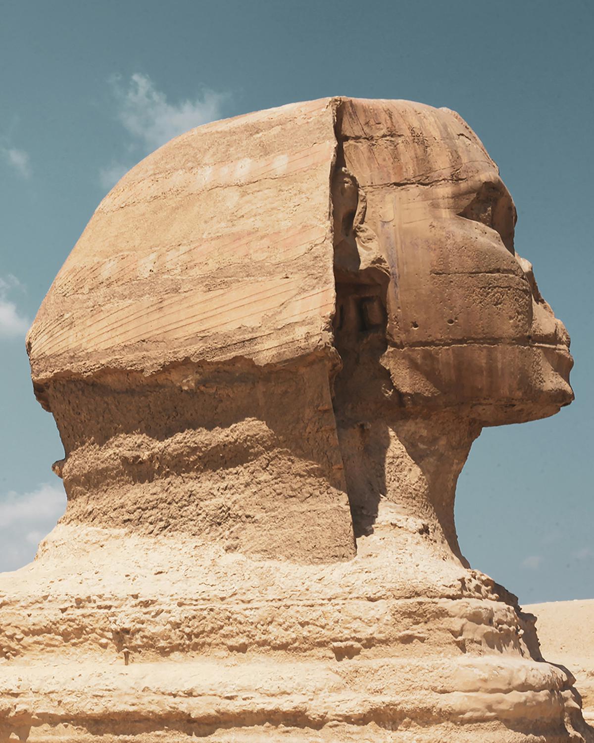 A close-up image of the Sphinx's face, highlighting her mysterious and enigmatic expression. The Sphinx's human-like features are combined with leonine and avian elements, creating a sense of otherworldly wisdom and power.