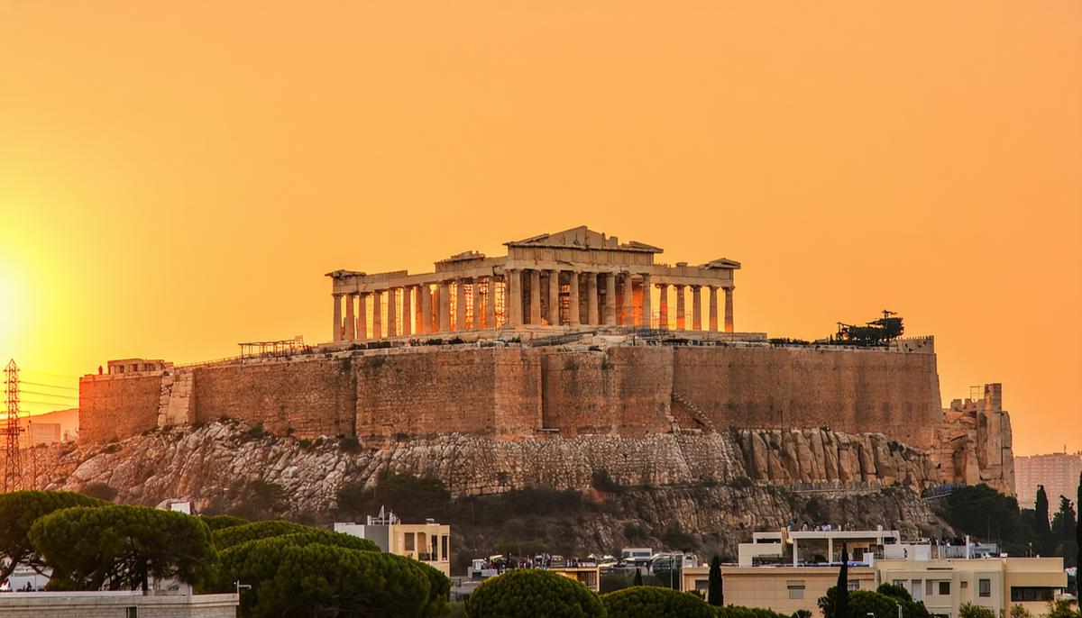 The Acropolis of Athens at sunset, with the Parthenon silhouetted against an orange sky