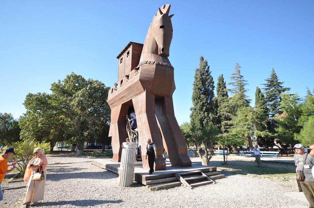 The archaeological site of Troy with ancient stone walls and a large wooden horse statue, symbolizing the famous Trojan Horse