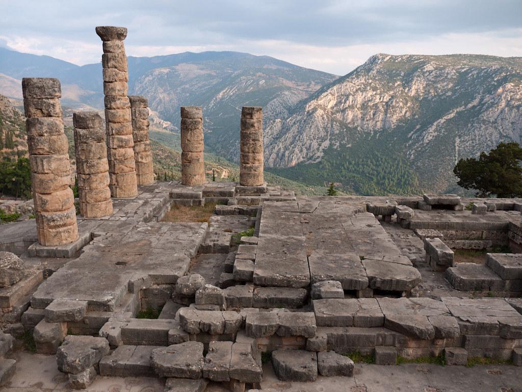 The ruins of the Temple of Apollo at Delphi, perched on the slopes of Mount Parnassus with a view of the valley below